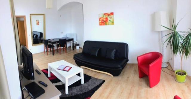 a living room with a black couch and red chairs at Hotel-Restaurant Windsor in Mondorf-les-Bains