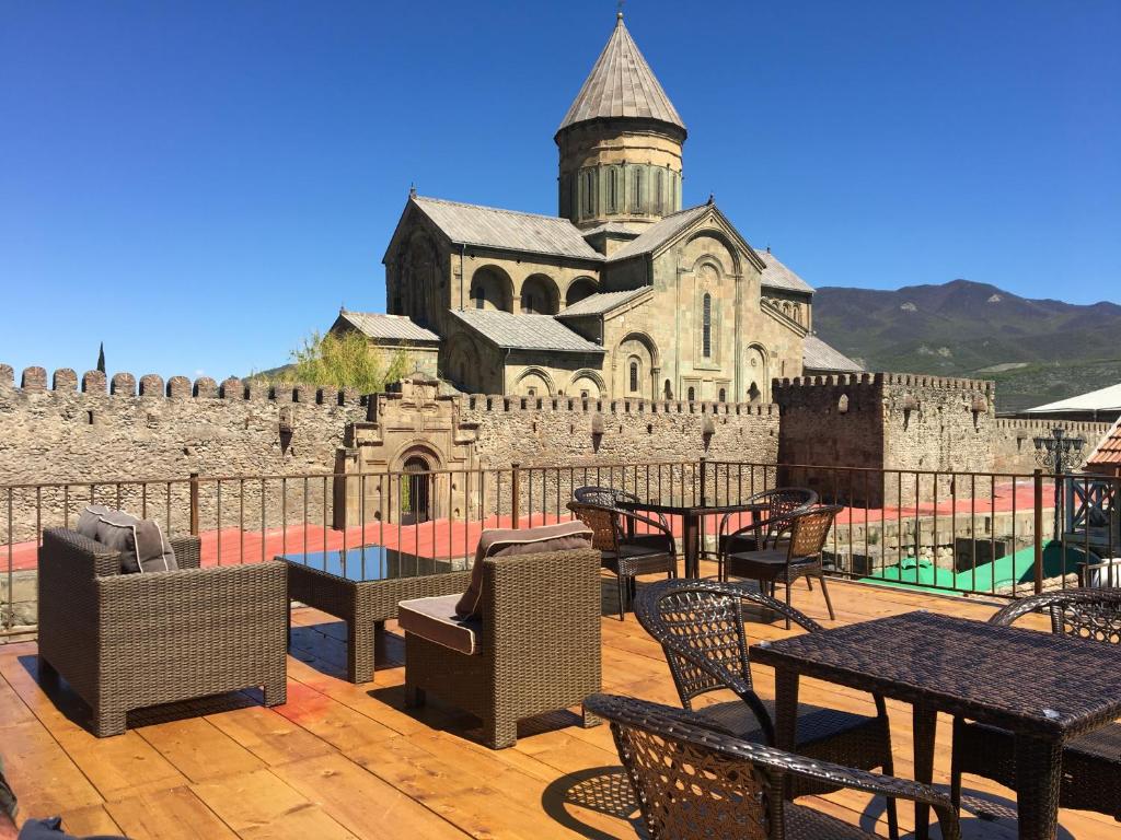 a patio with tables and chairs in front of a castle at Tamarindi Guest House in Mtskheta