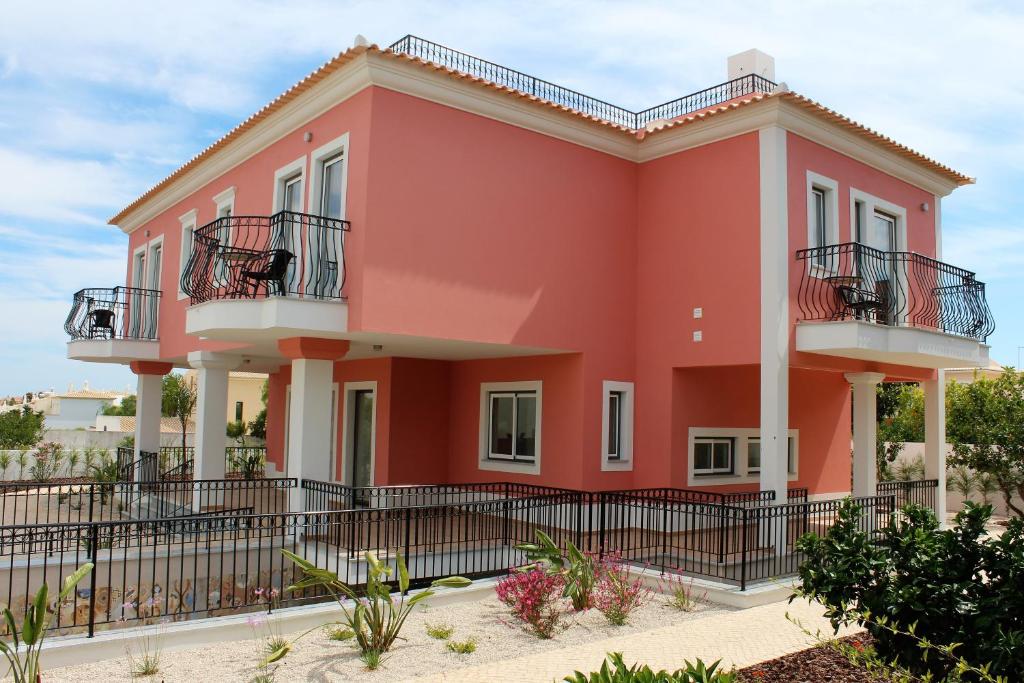 a red house with a black fence in front of it at Terraco do Solar Guest House in Lagos