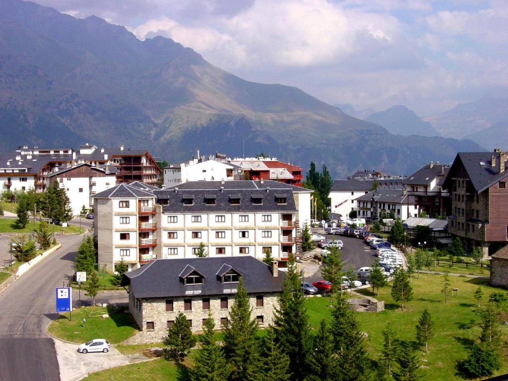 una ciudad con un edificio y montañas en el fondo en Hotel Nievesol, en Formigal