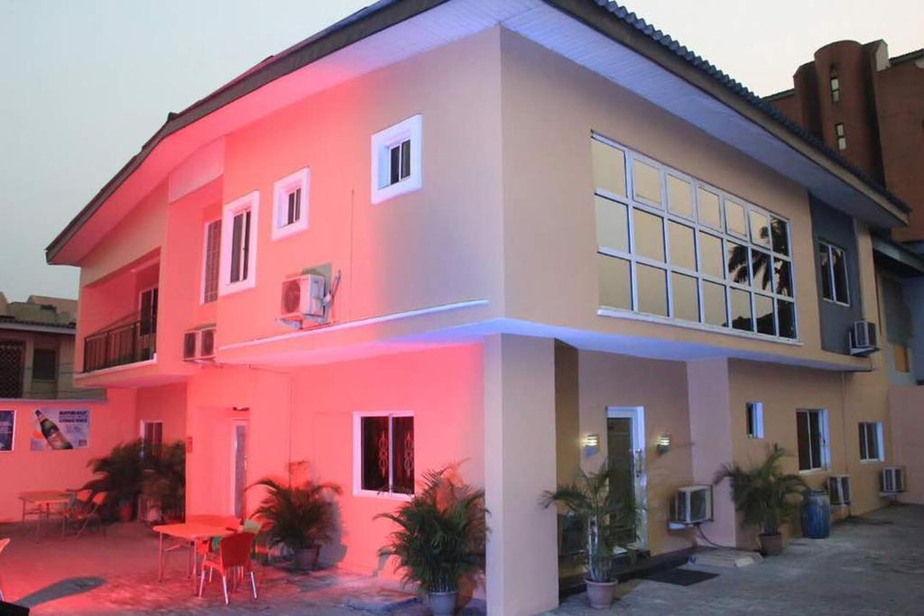 une maison rose avec une table devant elle dans l'établissement Chantella Suites, à Ikeja