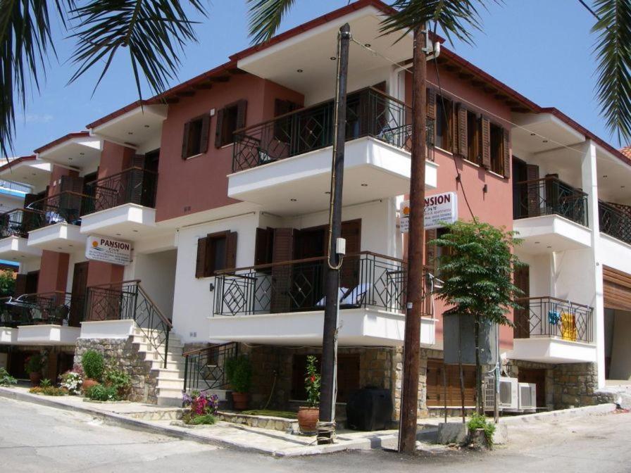 un edificio de color rosa y blanco con balcones y palmeras en Pansion Evi, en Ammoulianí