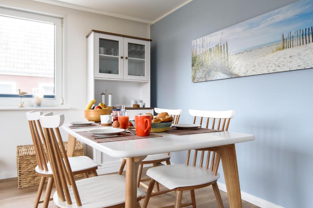 ein Esszimmer mit einem weißen Tisch und Stühlen in der Unterkunft Haus am Meer-Ferienwohnungen Sylt in Hörnum