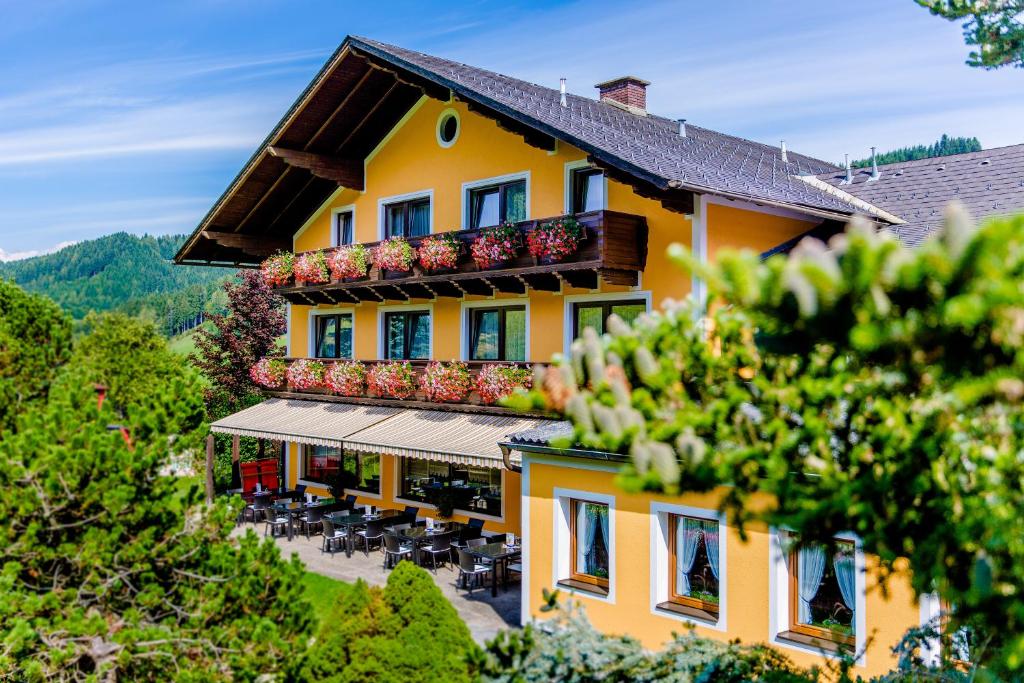 een geel gebouw met een balkon met tafels en stoelen bij Gasthof Landhotel Hubmann in Kleinlobming