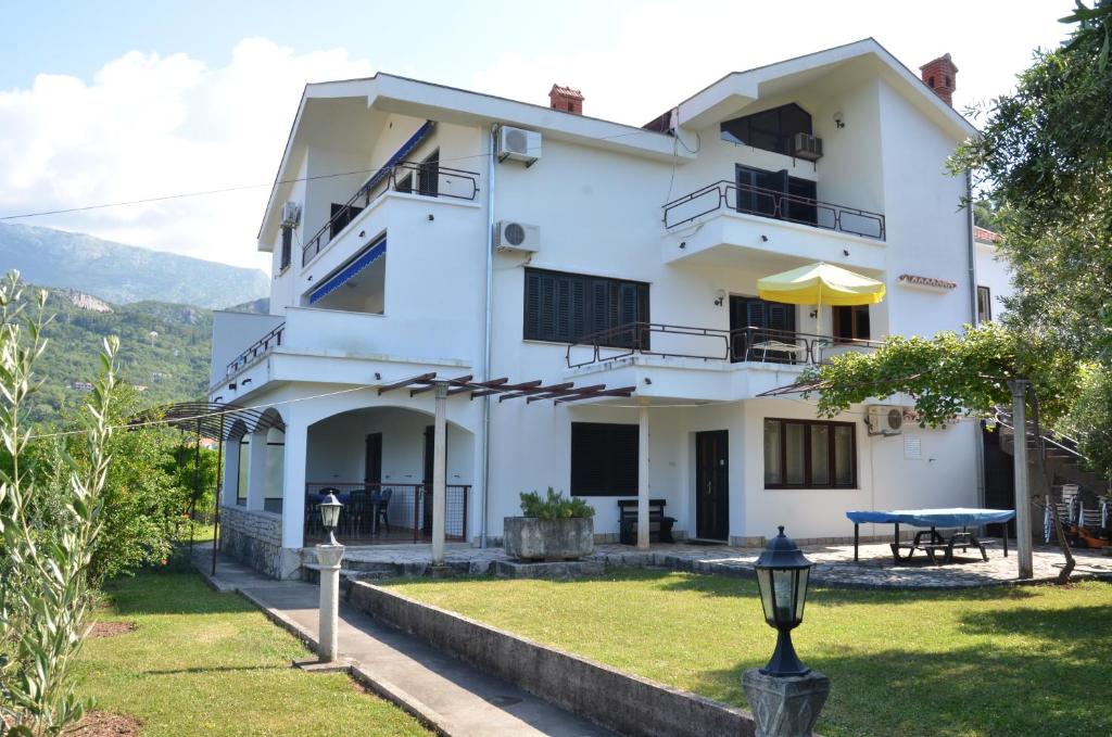 a white house with a picnic table in the yard at Apartmani Jasna in Herceg-Novi