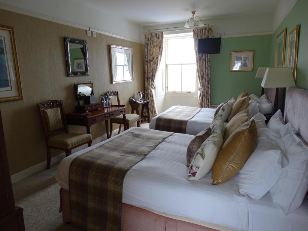 a hotel room with two beds and a desk at Port Charlotte Hotel in Port Charlotte