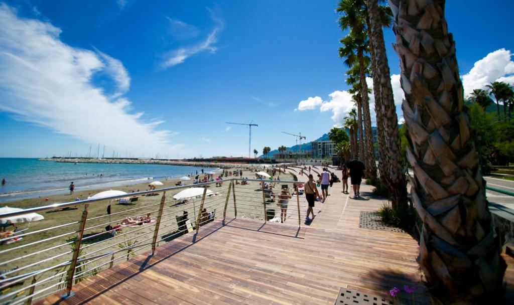 a beach with people walking on a wooden boardwalk at B&B degli Amalfitani in Salerno