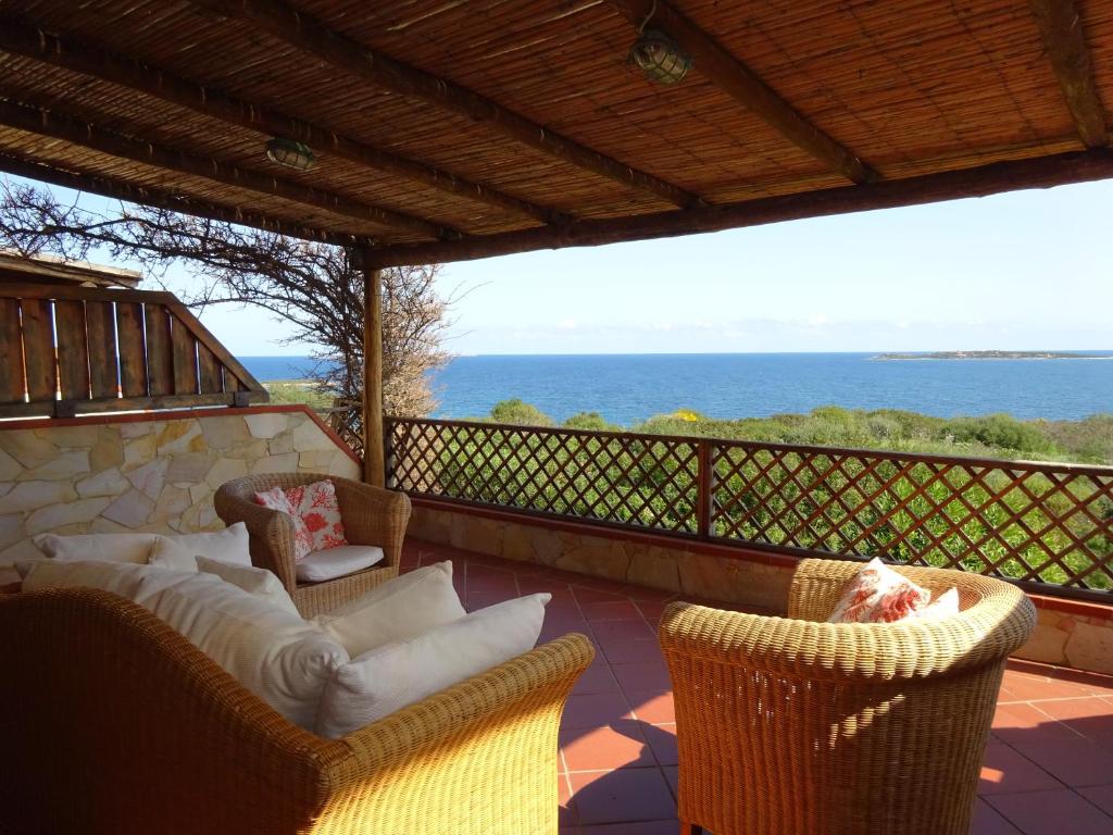 - une terrasse couverte avec des chaises en osier et une vue sur l'océan dans l'établissement Appartamento I Ginepri, à Marina di Portisco