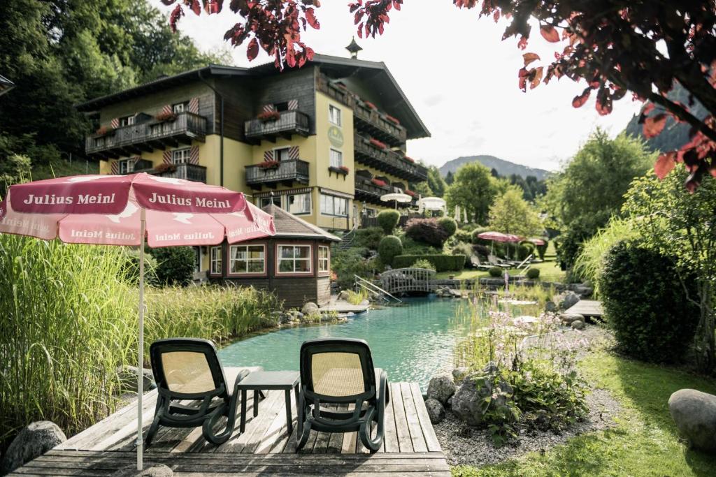 a couple of chairs and an umbrella next to a pond at Garni Haus Sonnleitn - Adults only in Fuschl am See