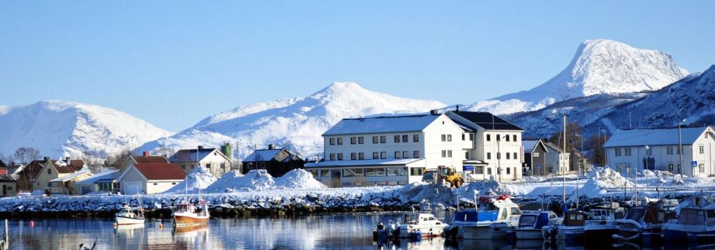 um porto com barcos na água com montanhas cobertas de neve em Reisafjord Hotel em Sørkjosen