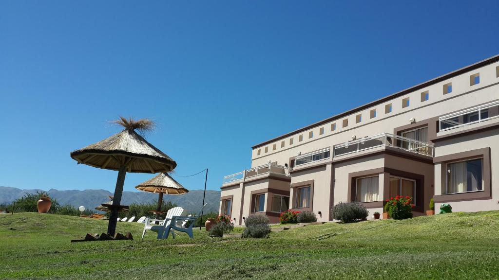 un edificio con sombrilla, mesa y sillas en Apart Hotel Vista San Lucas en Carpintería