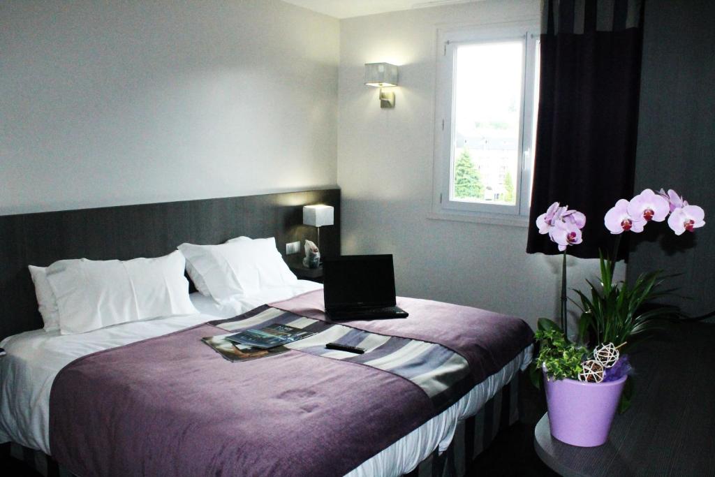 Habitación de hotel con cama con ordenador portátil en Hôtel des Rosiers, en Lourdes