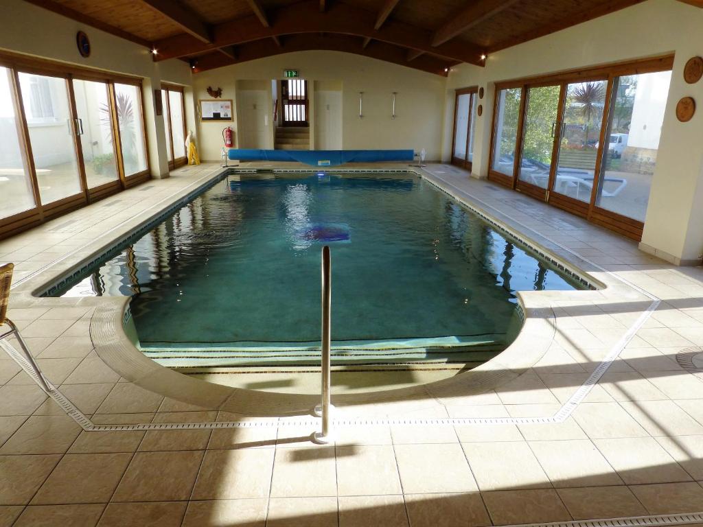 una piscina in un edificio con una grande stanza con finestre di The Norfolk Lodge Hotel a Saint Helier Jersey