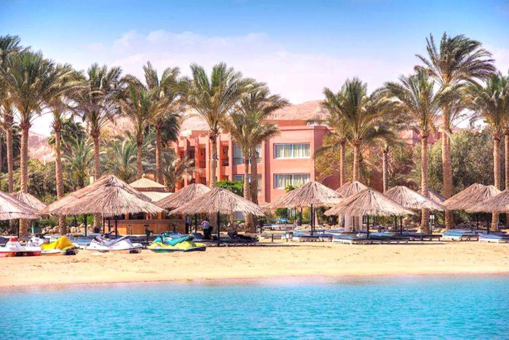 un complejo con una playa con sombrillas y palmeras en Kefi Palmera Beach Resort El Sokhna - Family Only en Ain Sokhna