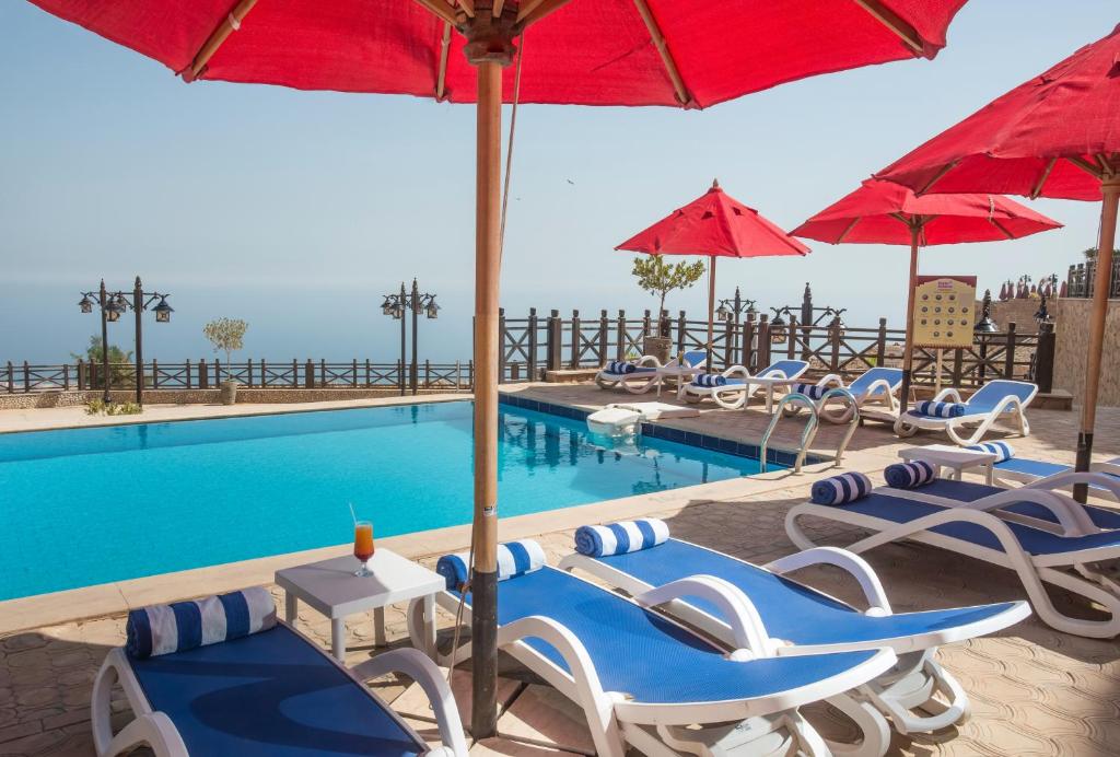 una piscina con tumbonas y sombrillas en Porto El Jabal Hotel en Ain Sokhna