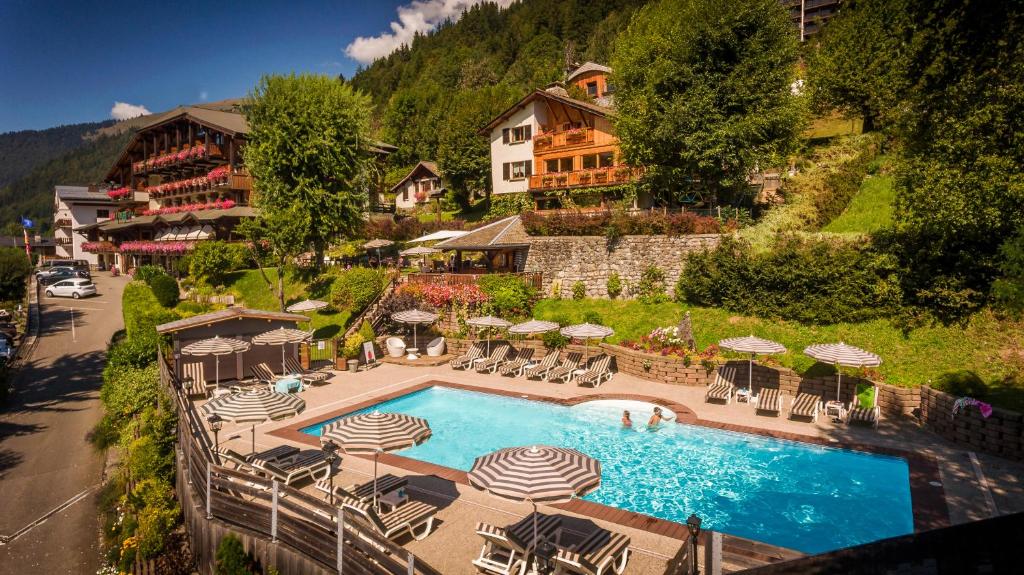 ein Pool mit Sonnenschirmen und Stühlen sowie ein Hotel in der Unterkunft Hotel & Spa Le Dahu in Morzine