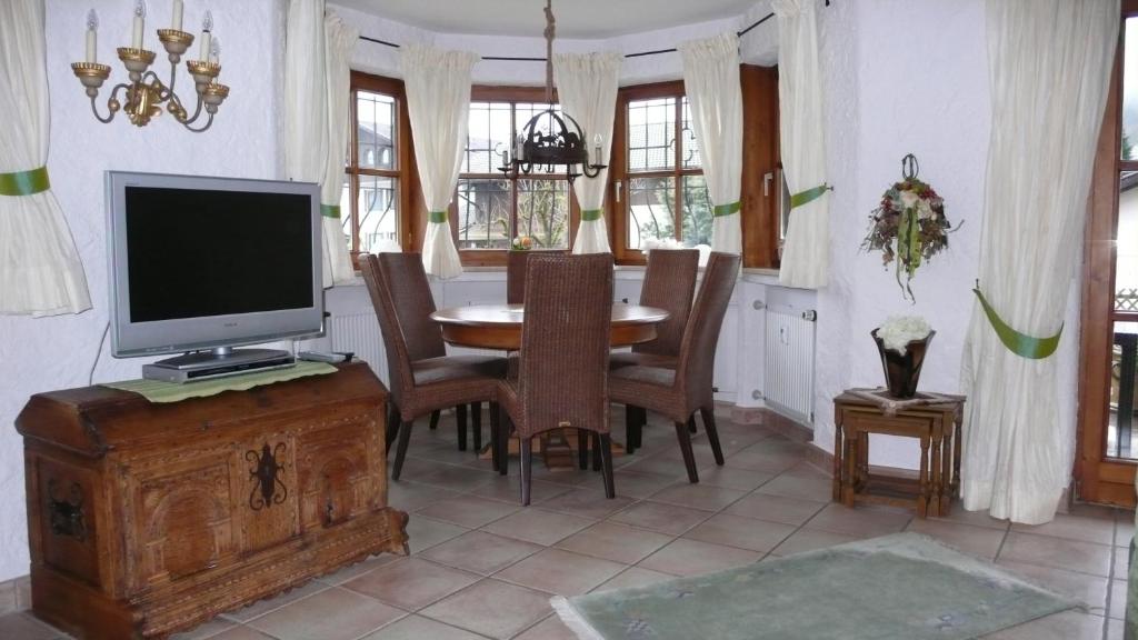 ein Esszimmer mit einem TV und einem Tisch mit Stühlen in der Unterkunft Apartment Xenia in Garmisch-Partenkirchen