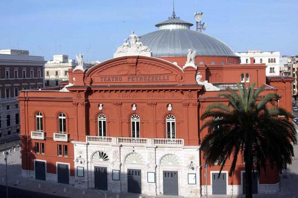 a large orange building with a palm tree in front of it at Giuseppe & Greta in Bari
