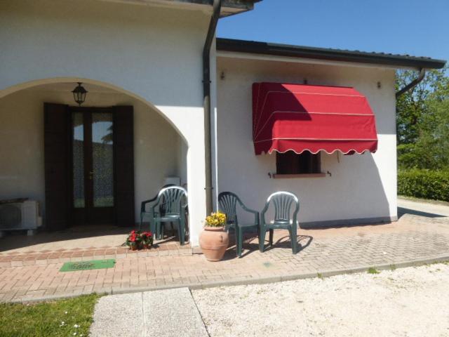 een patio met stoelen en een rode luifel op een huis bij Locazione Turistica alle Tre Civette in Noale