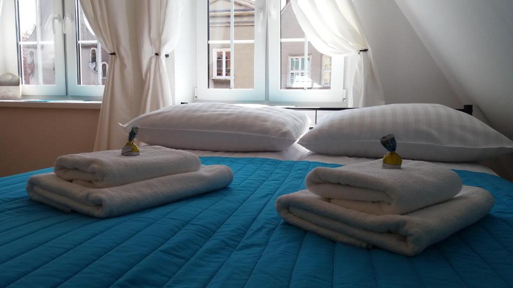 two beds with pillows on top of a blue bed at H&T Apartament przy Starym Żurawiu in Gdańsk