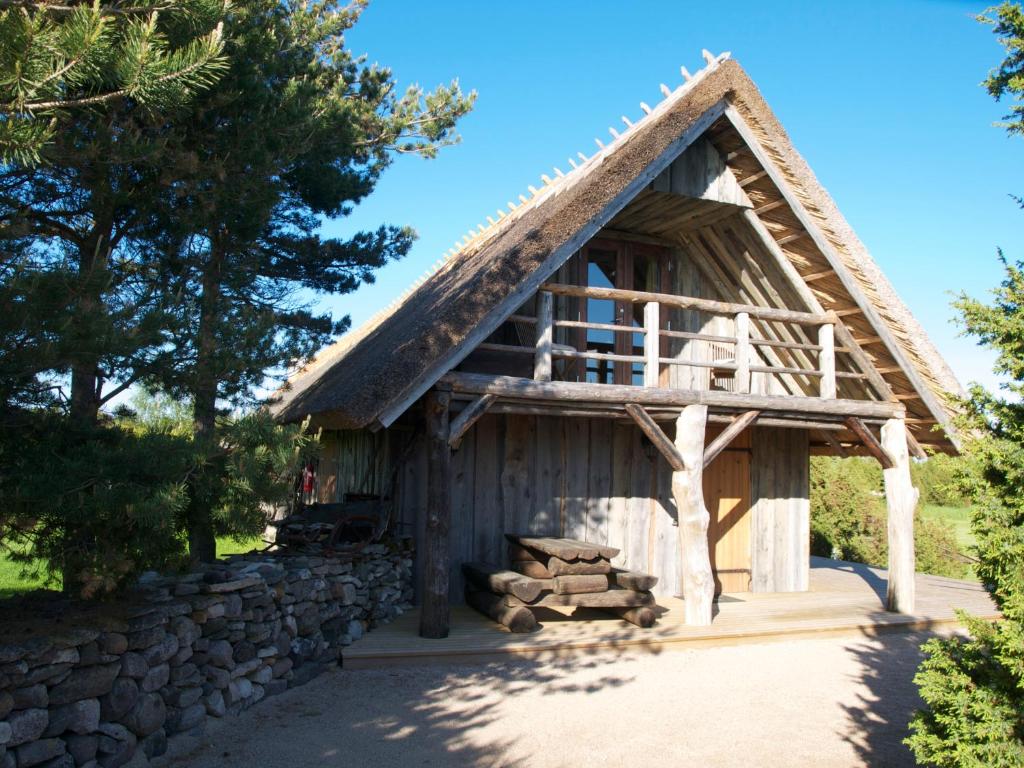 a log cabin with a thatched roof and a stone wall at Aaduaida Holiday House in Suur-Rootsi