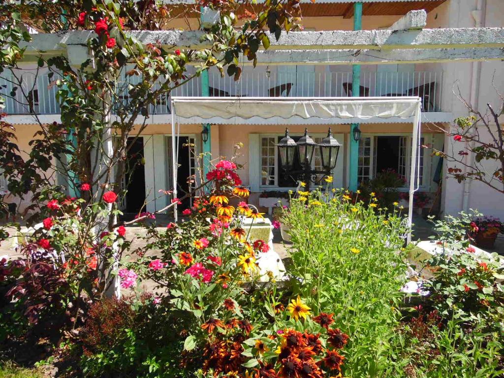 un jardín con flores frente a una casa en Hostellerie de La Poste, en Oust