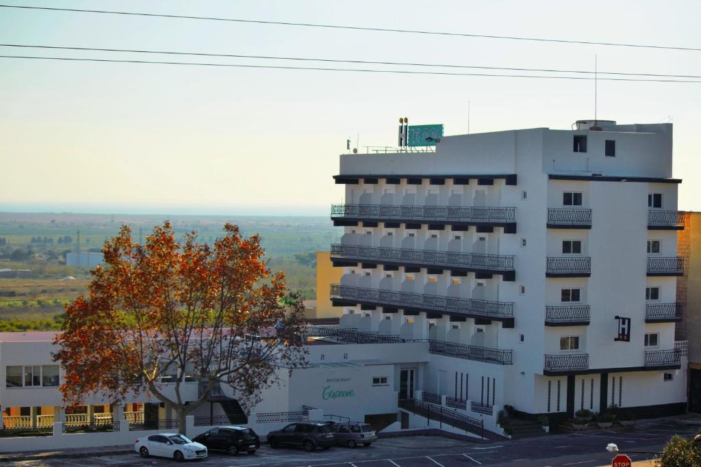 un bâtiment blanc avec des voitures garées dans un parking dans l'établissement Te Maná Hotel, à Torreblanca