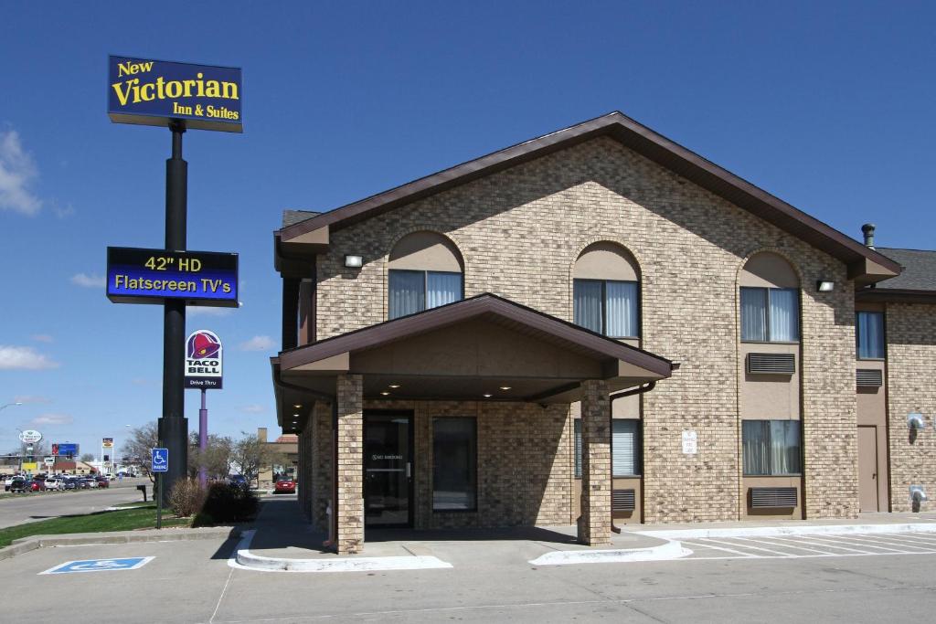 un hotel con un cartel frente a un edificio en New Victorian Inn & Suites Kearney, en Kearney