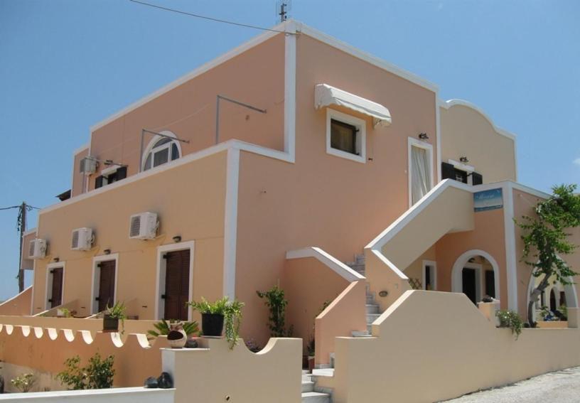 een roze huis met witte trap ervoor bij Mirsini Pansion in Karterados