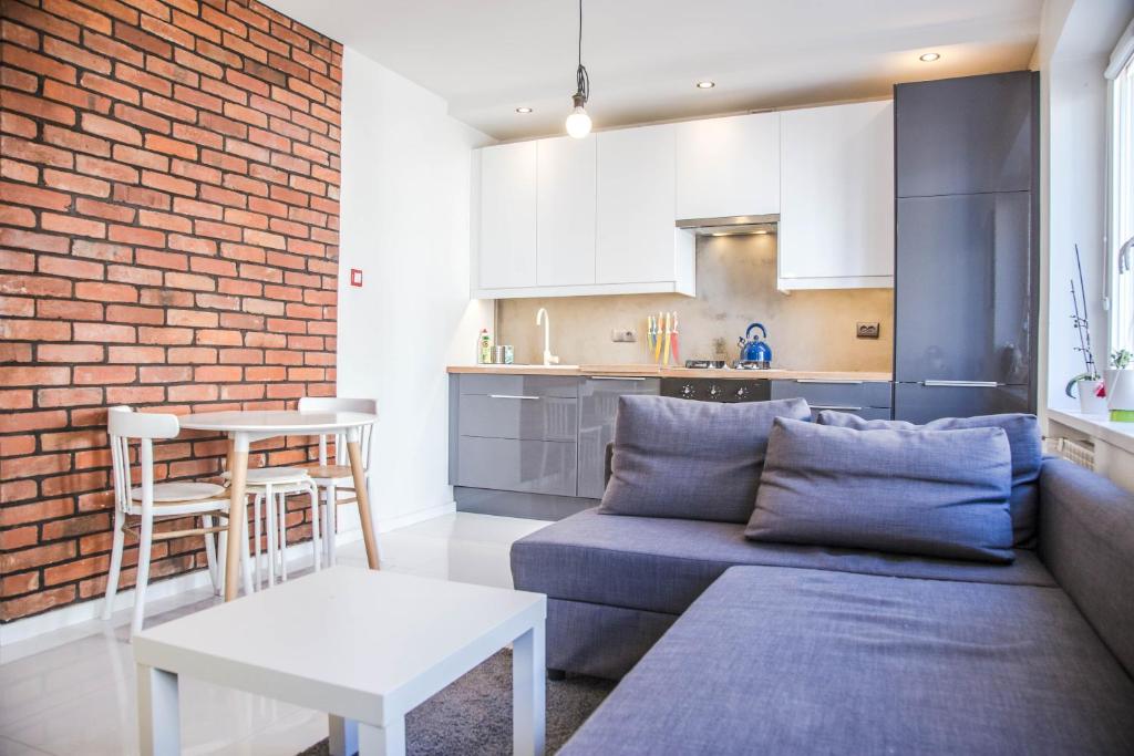a living room with a couch and a brick wall at Apartament Skwer Kosciuszki Gdynia Parking!! in Gdynia