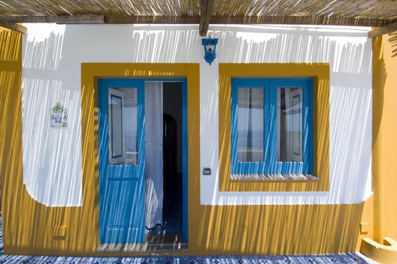 uma casa com portas e janelas azuis e amarelas em Hotel Girasole em Panarea