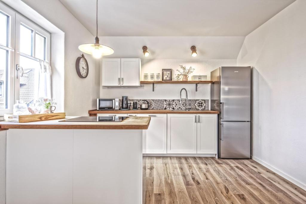 uma cozinha com armários brancos e um frigorífico de aço inoxidável em Ferienwohnung Eifelrausch em Berenbach