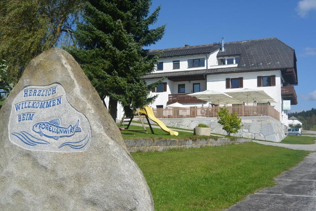 Una roca con un letrero junto a un patio de recreo. en Forellenwirt, en Grünbach