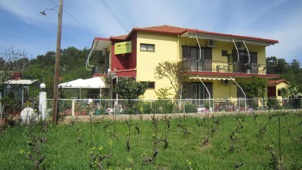 una casa amarilla con una valla delante de ella en Studios Ermis, en Kalamitsi