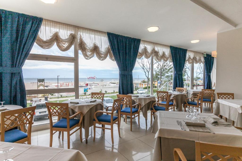 a restaurant with tables and chairs and a view of the beach at Hotel Astor in Rimini