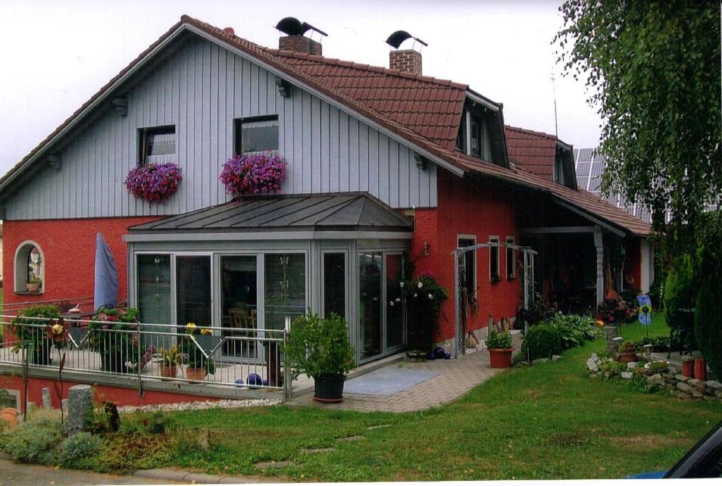 a red and white house with a greenhouse at Ferienwohnung Haus Monika in Rötz