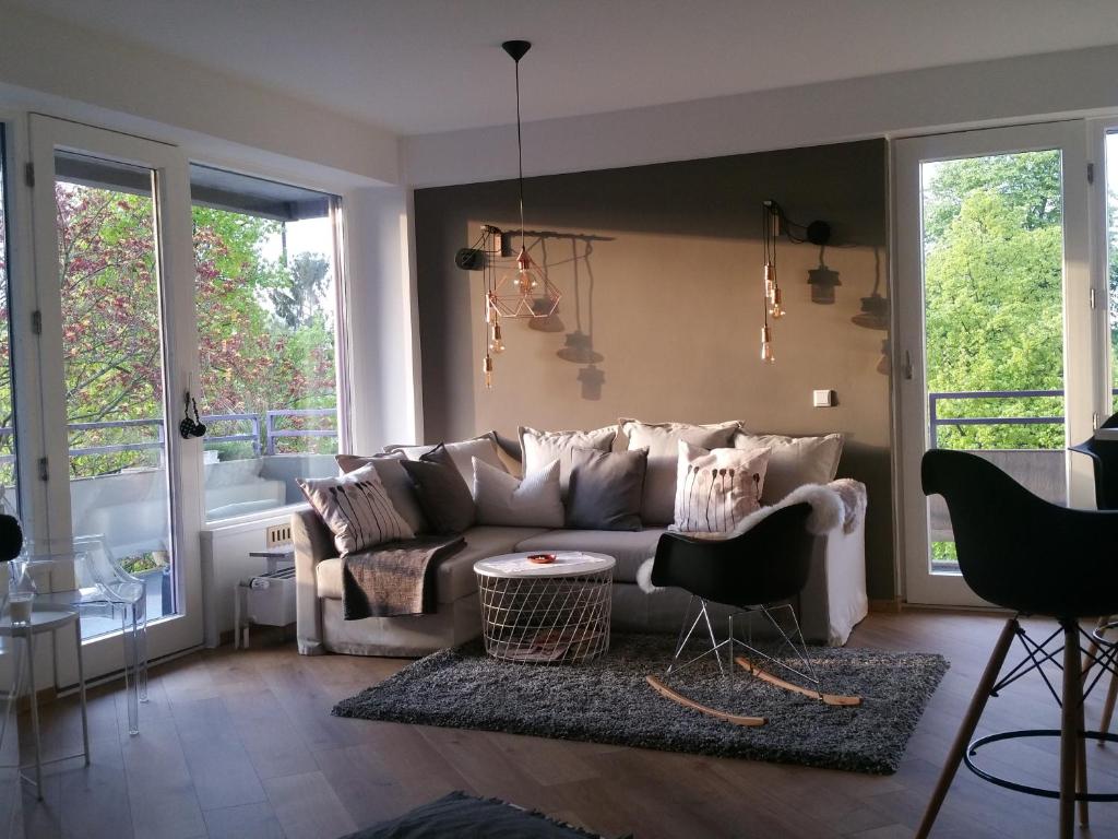 ein Wohnzimmer mit einem Sofa, Stühlen und Fenstern in der Unterkunft Apartment am Zoo in Krefeld