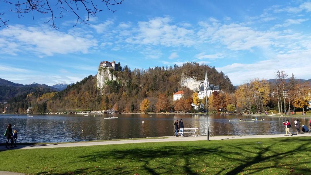 people walking on a sidewalk near a lake with a castle at Apartments Patricia in Bled