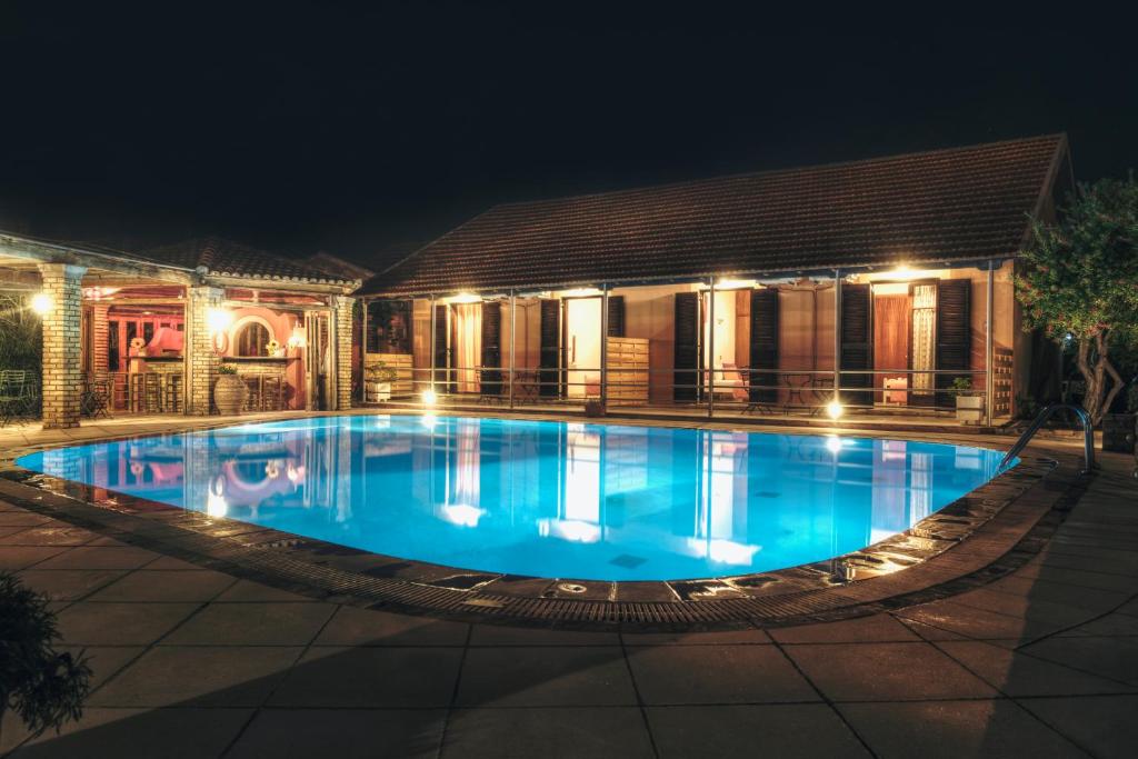a swimming pool in front of a house at night at HYGGE Corfu in Sidari