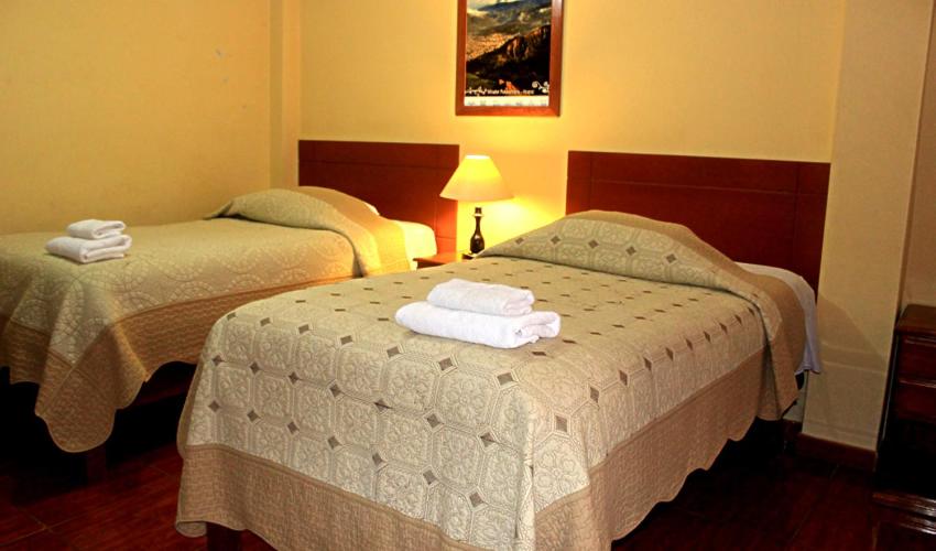 two beds in a hotel room with towels on them at Hotel Tamia in Huaraz