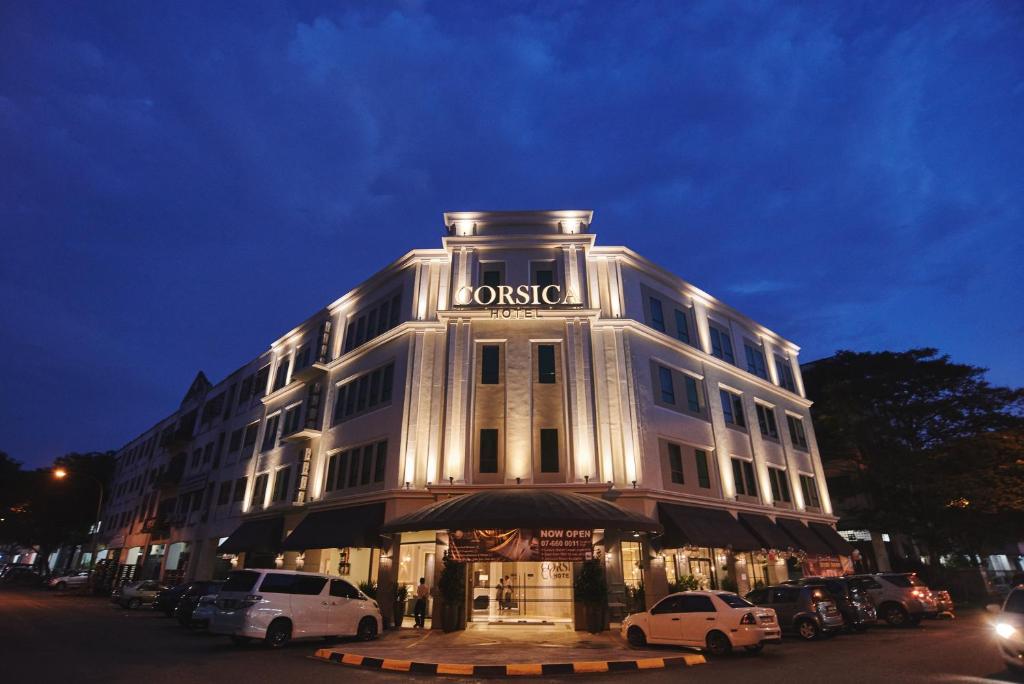 een groot wit gebouw met een bord erop bij Corsica Hotel in Kulai