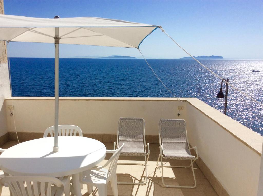 a balcony with a table and chairs and an umbrella at Dimora Tipica Vista Mare in Marettimo