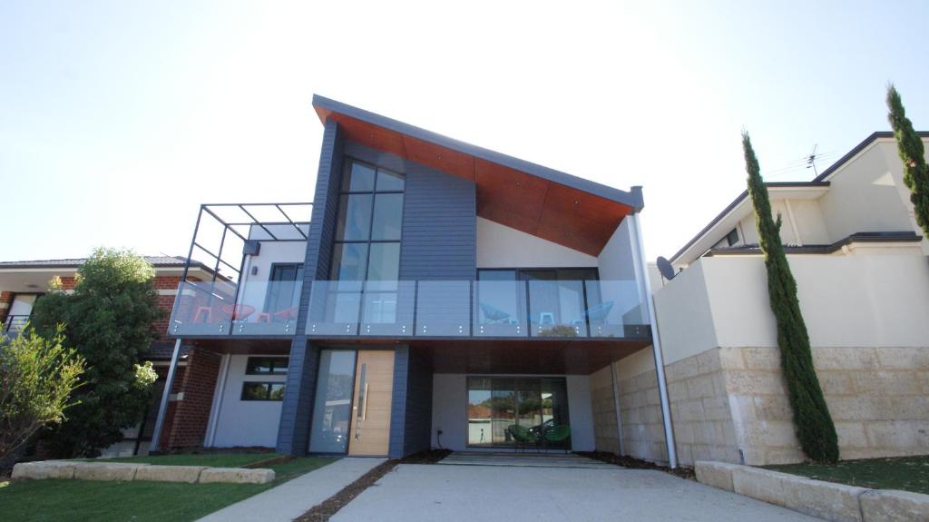 a house with a glass facade with a driveway at Sunset Place Apartments in Perth