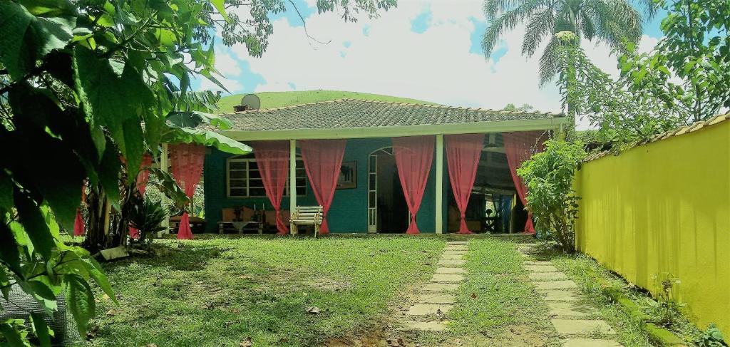 Casa da Yolanda - Hospedaria في ساو فرنسيسكو كزافييه: منزل أخضر وأحمر مع سياج أخضر