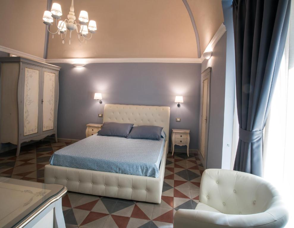 a bedroom with a white bed and a chair at Palazzo Bove in Galatone