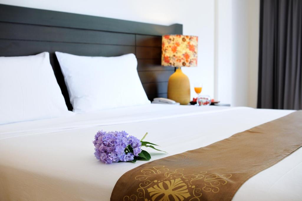 a bed with a bouquet of purple flowers on it at Kasemsarn Hotel Chanthaburi in Chanthaburi