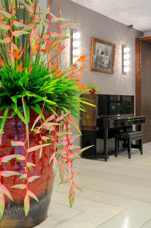 a large vase with plants in a room with a piano at Kasemsarn Hotel Chanthaburi in Chanthaburi
