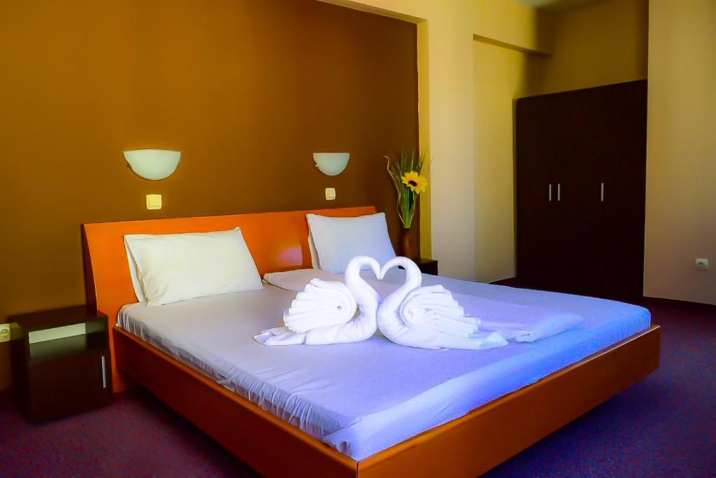 two white swans sitting on top of a bed at Hotel Alexander in Sofia
