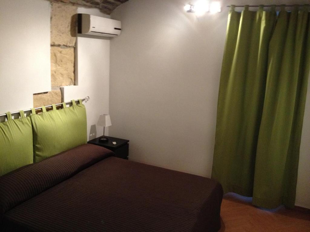 een slaapkamer met een bed en een groen gordijn bij InCentro Apartments in Milazzo