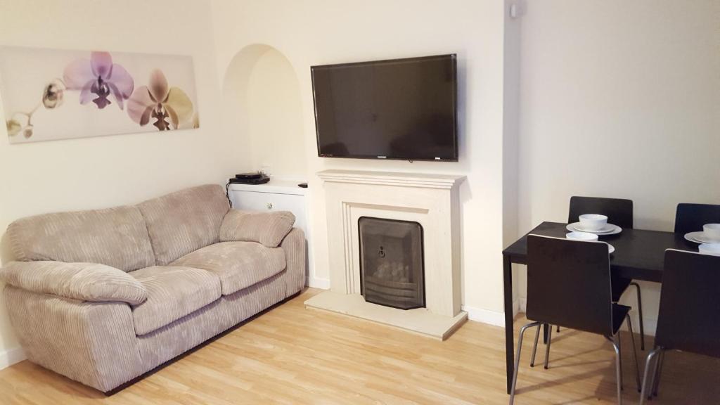 a living room with a couch and a tv over a fireplace at Workforce Property in Kirk of Shotts